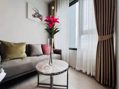 Stylish living room with modern decor and large window, featuring a cozy sofa and vibrant floral centerpiece.