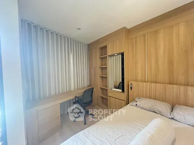 Modern bedroom with built-in wooden wardrobe and study desk, featuring a comfortable bed and sleek chair.
