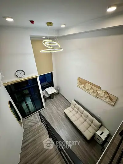 Modern loft-style living room with high ceiling and contemporary lighting