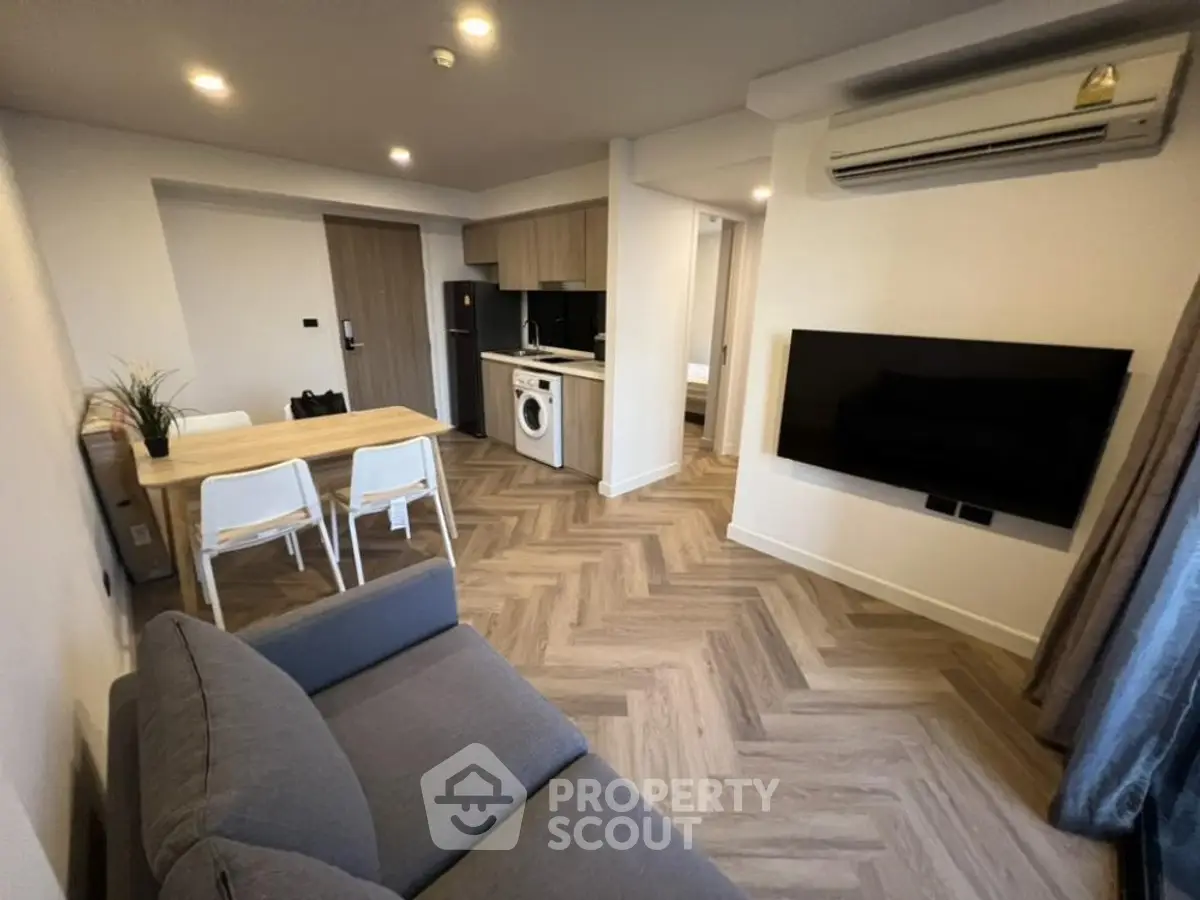 Modern living room with open kitchen, washing machine, and stylish decor.