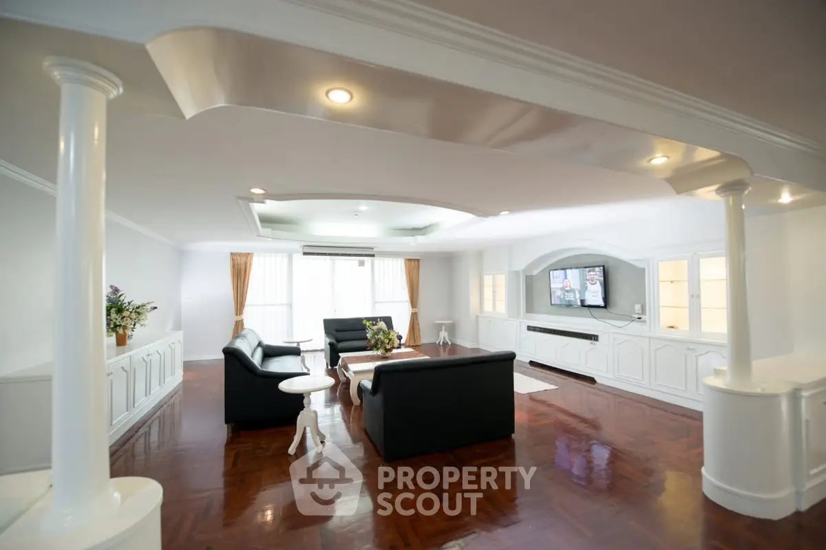 Spacious living room with elegant design and polished wooden floors, featuring modern furniture and ambient lighting.