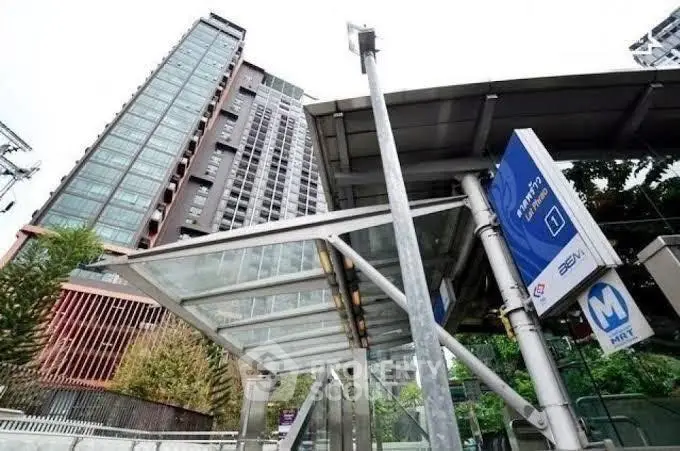 Modern urban building with adjacent MRT station entrance, showcasing convenient city living.
