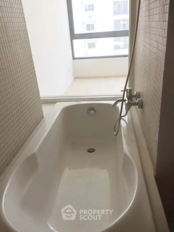 Modern bathroom with sleek bathtub and large window offering natural light.