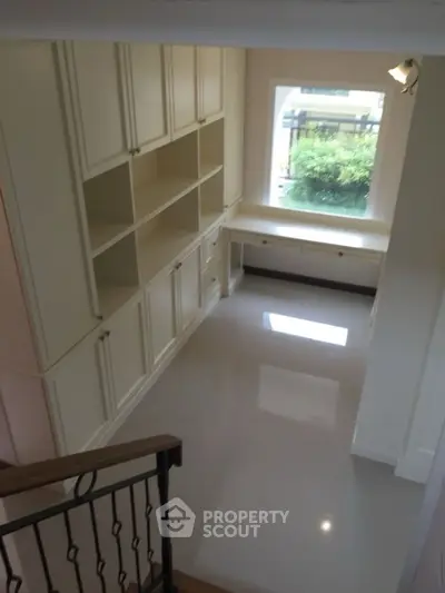 Spacious study room with built-in shelves and large window view