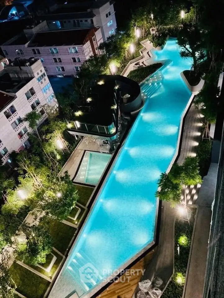 Stunning aerial view of illuminated outdoor pool in modern residential complex at night.