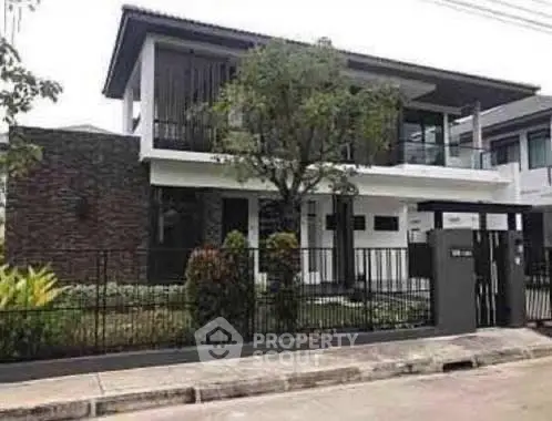 Modern two-story house with sleek design and landscaped front yard in a suburban neighborhood.