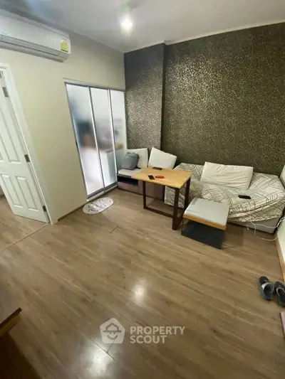 Cozy living room with modern decor and wooden flooring, featuring a comfortable sofa and stylish wallpaper.
