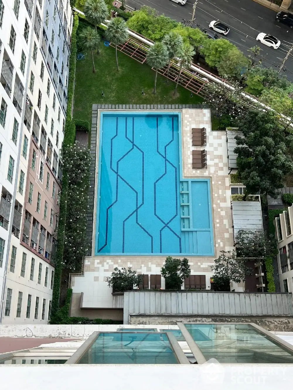 Stunning aerial view of modern apartment complex with luxurious swimming pool and lush garden area.