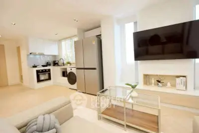Modern living room with open kitchen, featuring sleek appliances and stylish decor.
