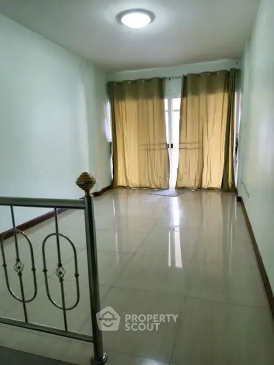 Spacious living room with elegant curtains and polished tile flooring.