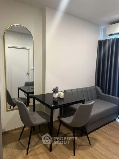 Modern living room with sleek black table and gray sofa, featuring elegant decor and wooden flooring.
