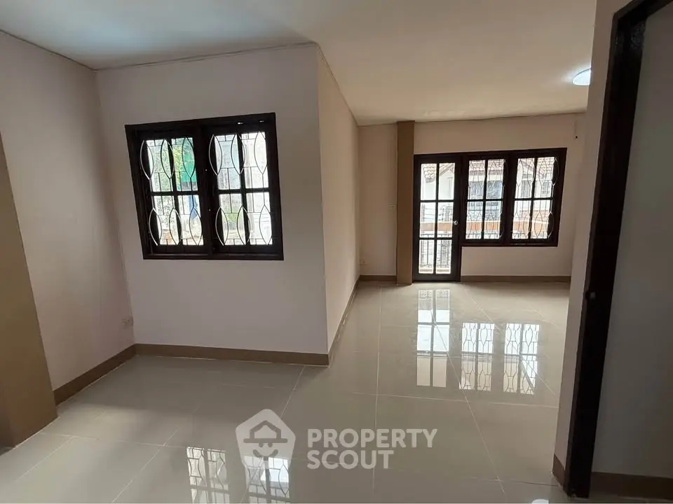 Spacious living area with large windows and glossy tiled floors