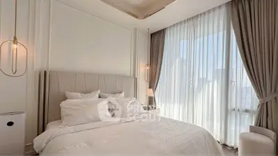 Luxurious bedroom with elegant decor and large window draped in sheer curtains