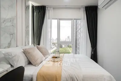 Modern bedroom with city view, featuring elegant decor and large windows.