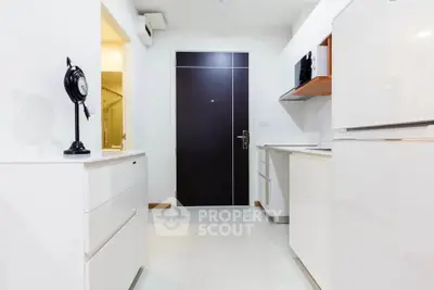 Modern kitchen with sleek white cabinets and appliances, featuring a minimalist design and ample storage space.