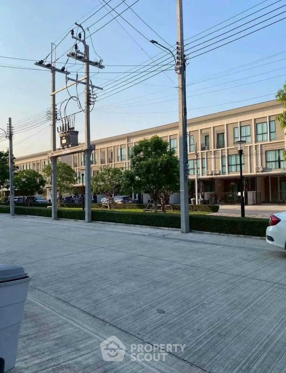 Modern townhouse complex with ample parking and lush greenery.