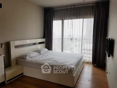 Spacious bedroom with large windows and modern furnishings in a high-rise apartment.