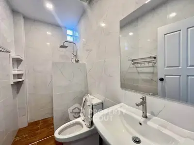 Modern bathroom with sleek fixtures and marble tiles, featuring a shower and a spacious sink area.