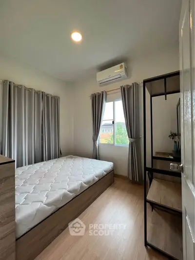 Cozy bedroom with natural light, featuring a comfortable bed and modern decor.