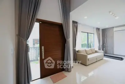 Modern living room with elegant curtains and a cozy sofa, featuring a wooden door and ample natural light.