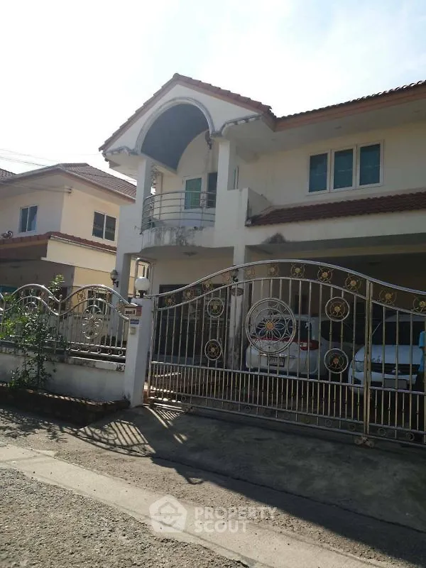 Charming two-story house with gated entrance and balcony in a sunny neighborhood.