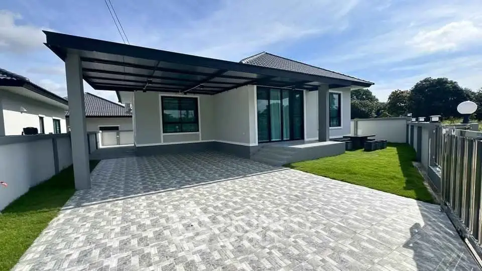 Modern single-story house with spacious driveway and lush green lawn.