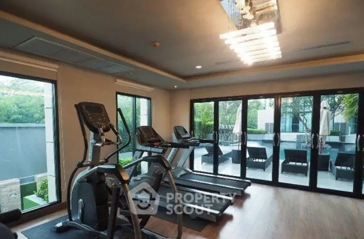 Modern gym with treadmills and large windows overlooking greenery