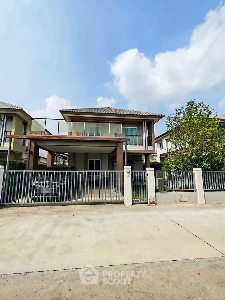 Modern two-story house with spacious driveway and gated entrance in suburban neighborhood.