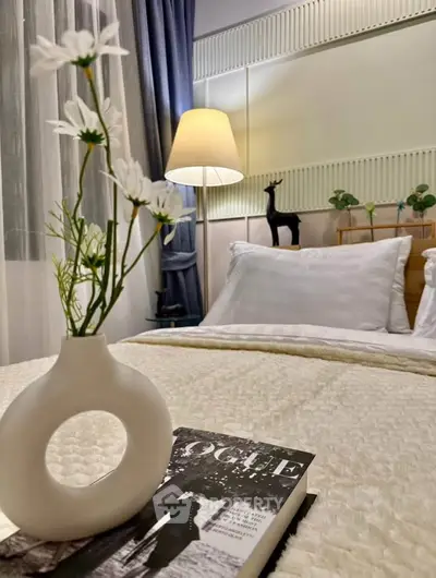 Cozy bedroom with elegant decor and soft lighting, featuring a stylish vase and magazine on the bed.