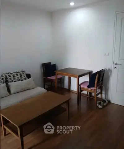 Cozy living room with wooden flooring, sofa, and dining table set.