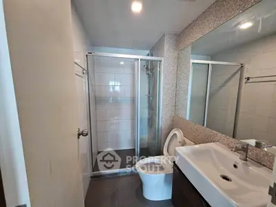 Modern bathroom with glass shower enclosure and sleek vanity in a contemporary home.
