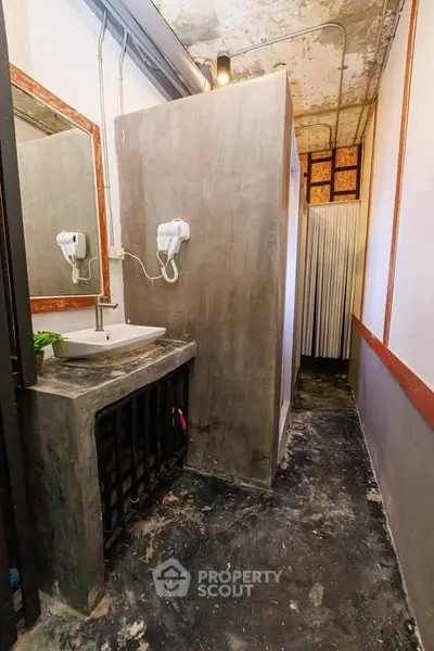 Industrial-style bathroom with concrete sink and exposed ceiling pipes