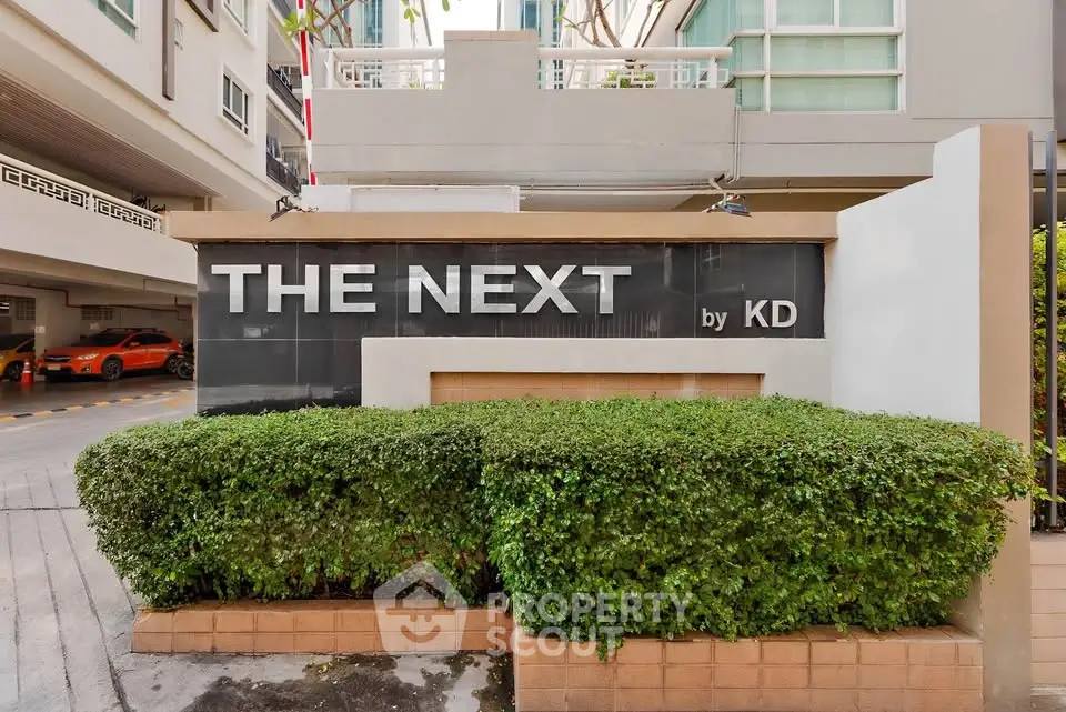 Modern building entrance with lush greenery and stylish signage.