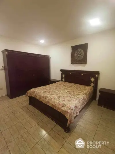 Spacious bedroom with classic wooden furniture set and tiled flooring, offering a comfortable and timeless living space.