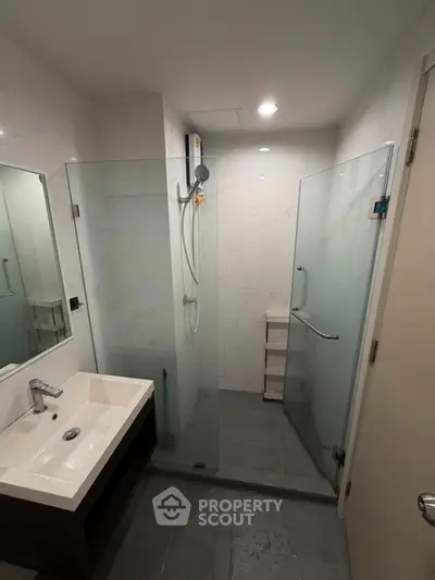Modern bathroom with glass shower enclosure and sleek vanity in a contemporary apartment.