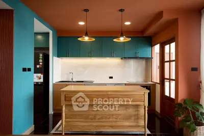 Modern kitchen with vibrant colors and wooden island, featuring pendant lighting and sleek cabinetry.