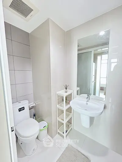 Modern bathroom with sleek fixtures and neutral tones, featuring a wall-mounted sink and toilet.