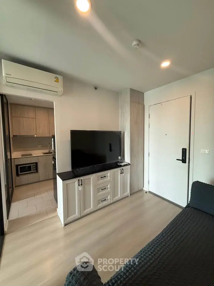 Modern living room with sleek TV stand and open kitchen layout in stylish apartment.