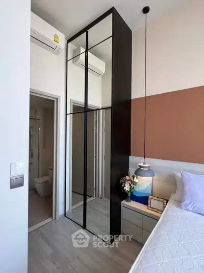 Modern bedroom with mirrored wardrobe and stylish lighting in a contemporary apartment.