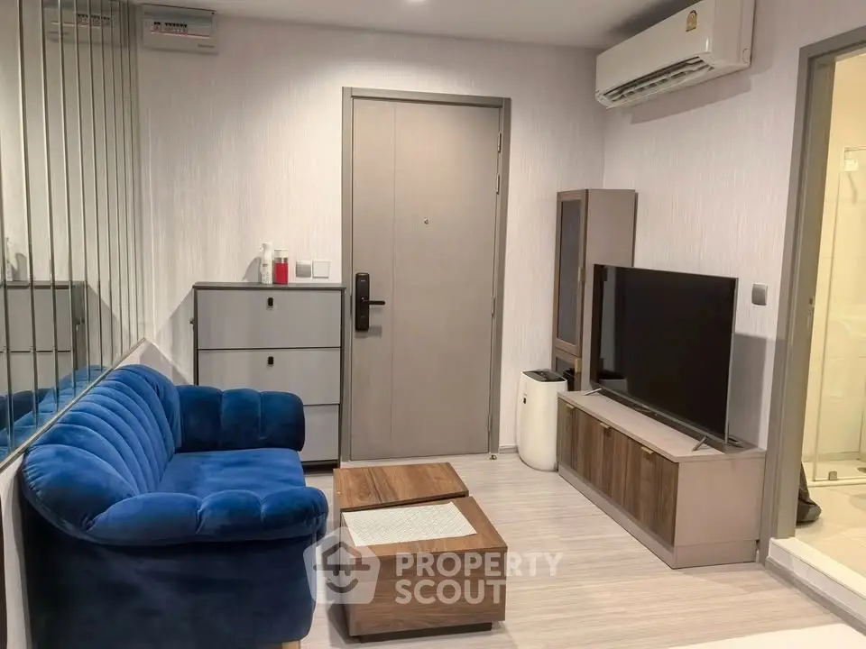 Modern living room with blue velvet sofa, sleek TV unit, and mirrored wall for spacious feel.