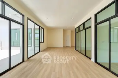 Spacious modern room with large windows and wooden flooring, ideal for versatile living space.
