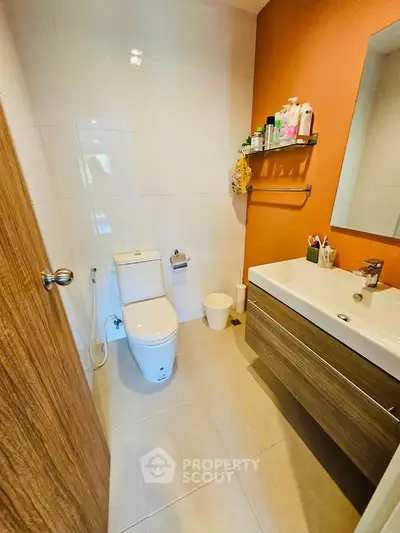 Modern bathroom with sleek fixtures and warm orange accent wall