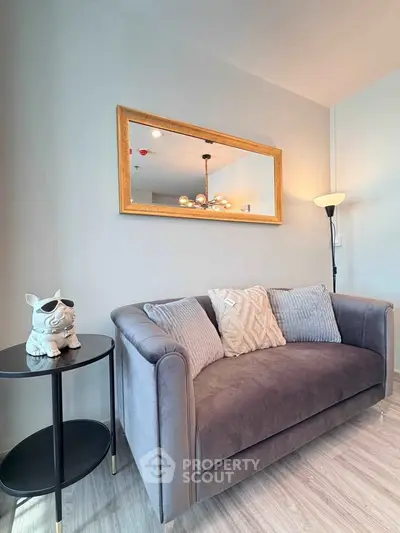Stylish living room with plush gray sofa, elegant mirror, and chic decor for modern comfort.