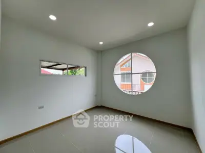 Bright room with unique circular window and glossy tiled floor, perfect for modern living.