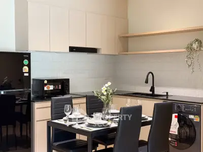 Modern kitchen with sleek cabinetry, dining table, and built-in appliances in a stylish apartment.