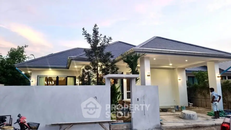 Modern single-story house with sleek roof design and spacious front yard under a beautiful sky.