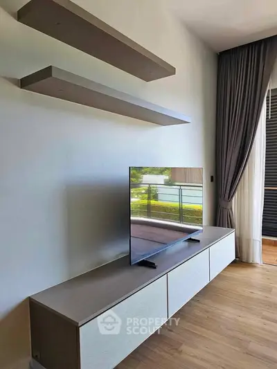 Modern living room with sleek TV stand and floating shelves, featuring a view of the balcony.