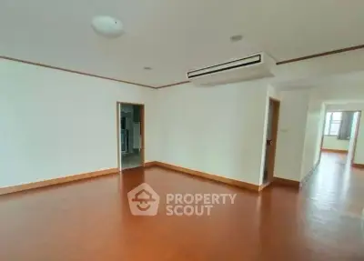 Spacious empty room with wooden flooring and air conditioning, ideal for customization.