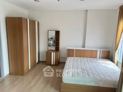 Spacious bedroom with modern wooden furniture and large window for natural light.