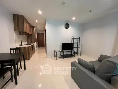 Modern open-plan living room with sleek kitchen and stylish furnishings in a contemporary apartment.